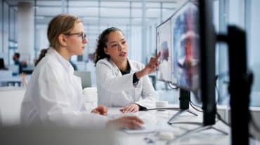 Two dentists work together on a computer. Learn how DSOs work in dentistry, why orthodontics is different, and how doctor-owned OSO partnerships compare on equity and autonomy.