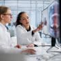Two dentists work together on a computer. Learn how DSOs work in dentistry, why orthodontics is different, and how doctor-owned OSO partnerships compare on equity and autonomy.