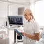 A female dentists looks at a tablet. Discover why solo orthodontic practices hit a growth ceiling and what successful doctors do differently to break through it.