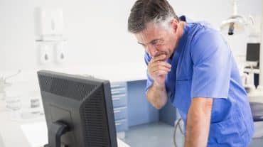 An orthodontist looks at a computer. Learn how DSOs and OSOs generate returns, where private equity fits in, and how doctor-owned models differ before you evaluate a partnership offer.