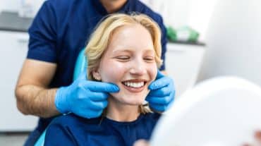 Happy young woman smiling at an orthodontist appointment. Learn how orthodontic practice valuation works, from EBITDA multiples to the factors that actually move your number, and why the report figure isn't your final payout.