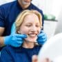 Happy young woman smiling at an orthodontist appointment. Learn how orthodontic practice valuation works, from EBITDA multiples to the factors that actually move your number, and why the report figure isn't your final payout.
