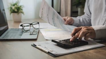 A person reviewing business finances. Rising student debt is changing who can buy an orthodontic practice. What the shift means whether you're buying, selling, or hiring.